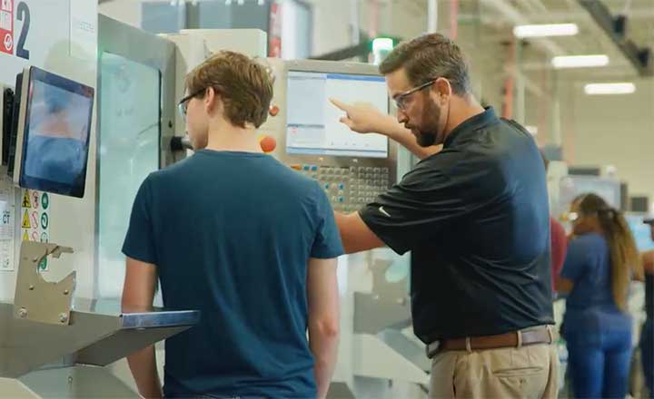 Image of a CNC machining instructor showing a student how to use equipment